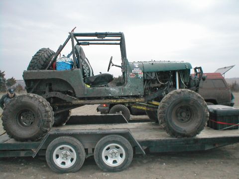 1983 Ford Bronco - Customized Jeep CJ-7 loaded onto a trailer, with a red SUV visible in the background.
