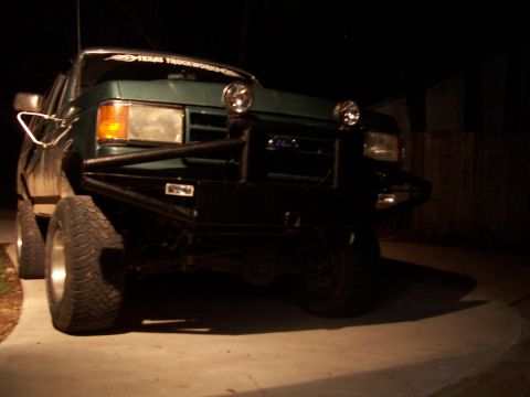 1989 Ford Bronco - Frontal view of a green Ford truck with a custom bumper and auxiliary lights, likely from the late 1980s.