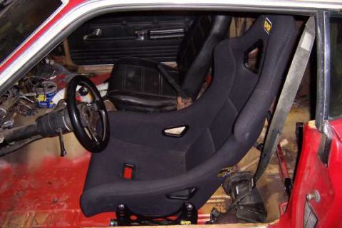 1971 Ford Mustang - Interior view of a car showing a racing seat and steering wheel, with exposed wiring.