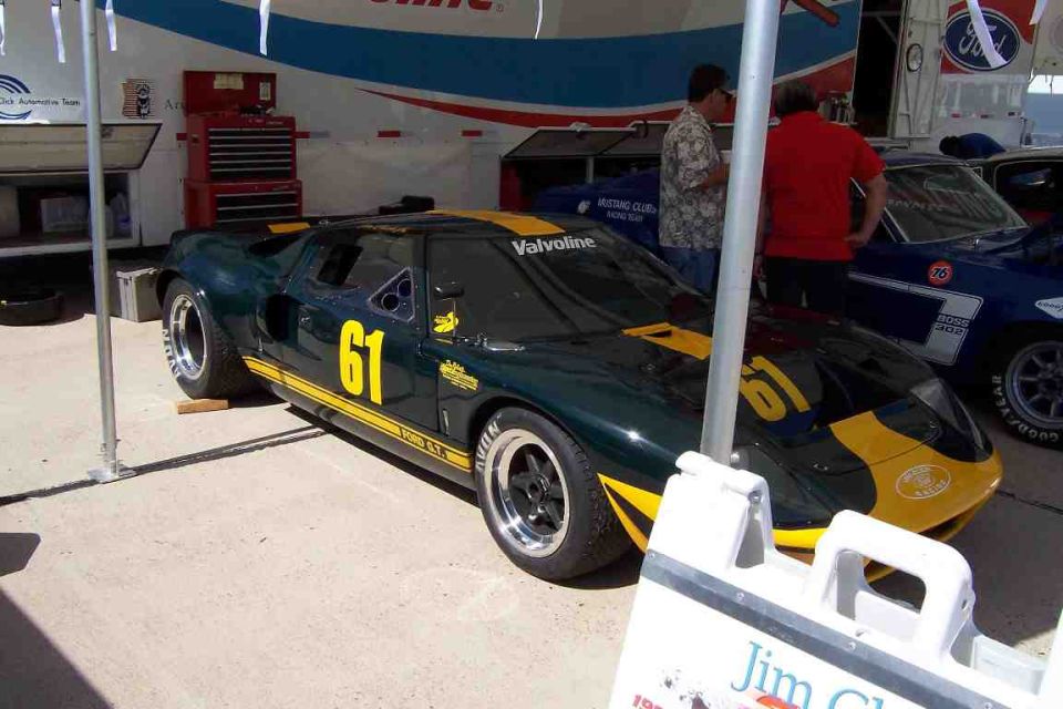 Green and yellow Ford GT40 race car with number 61, parked next to a blue Mustang