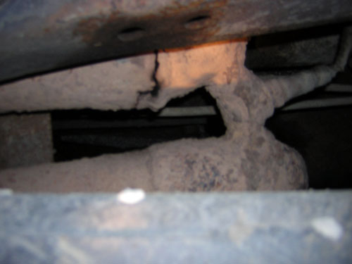 rusted exhaust pipe and frame under a vehicle