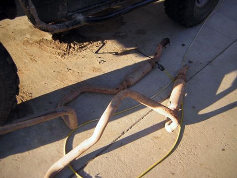 1995 Ford Bronco - The vehicle's exhaust system components are laid out on the ground for inspection or modification.