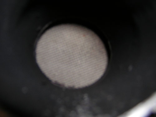 Close-up of a circular exhaust pipe screen with a fine mesh