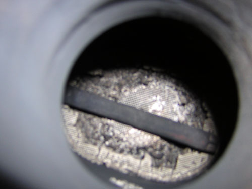 Interior view of a dirty exhaust pipe with a catalytic converter grid