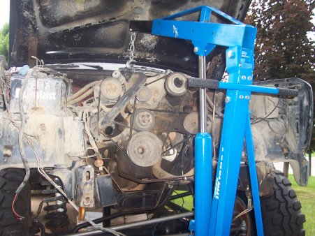 1986 Ford Bronco - Engine bay with engine hoist lifting the engine, showing exposed wires and hoses.