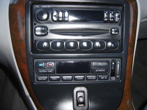 1997 Lincoln Mark VIII - Close-up of a car's dashboard showing the radio and climate control panel, wood grain accents and various function buttons.