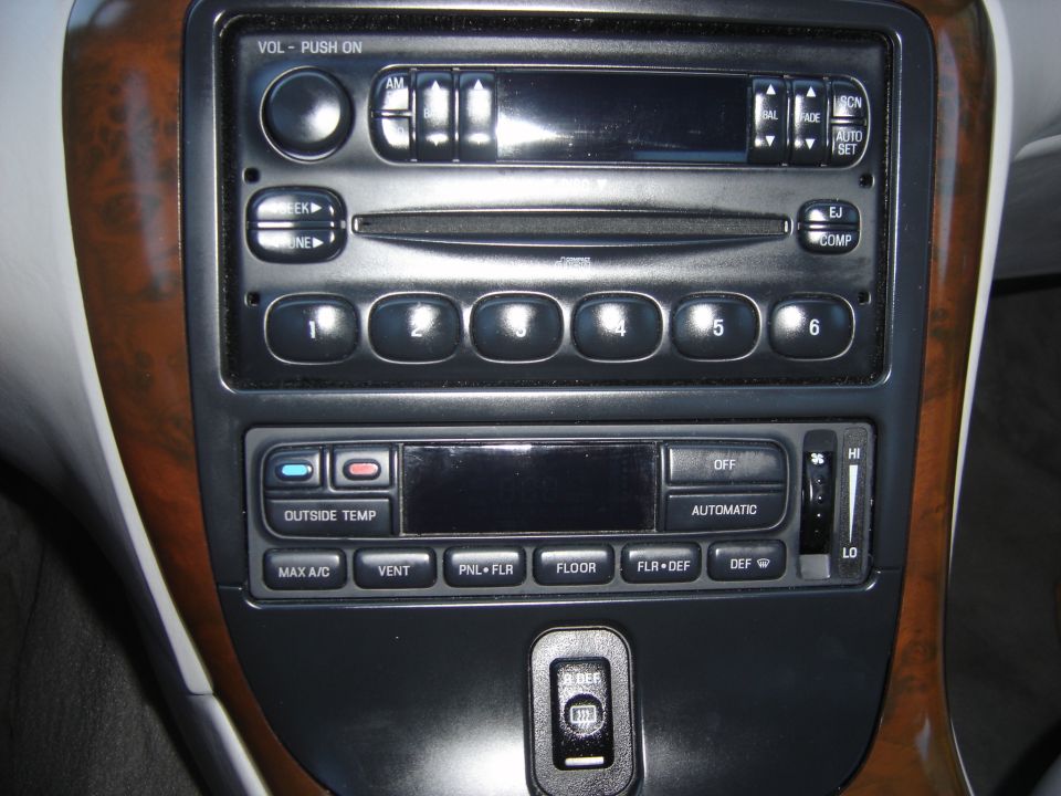 Car interior dashboard with wood trim, radio, and climate controls. Includes buttons for 'MAX A/C', 'VENT', 'FLOOR', and 'DEF'