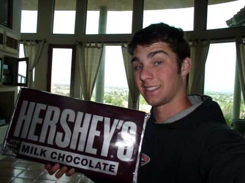 1990 Ford Bronco - A person poses for a selfie while holding a giant Hershey's milk chocolate bar in front of a large window.