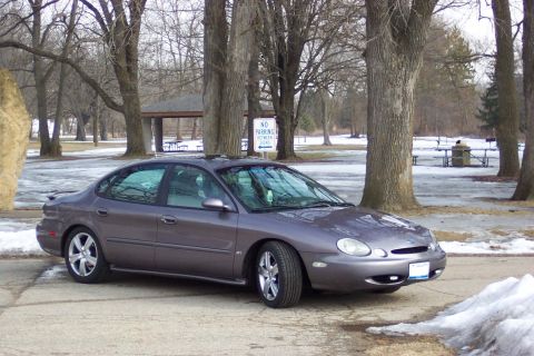 1996 Ford Taurus - Sedan parked in a park during winter. The car's body style suggests a model year around 2000.