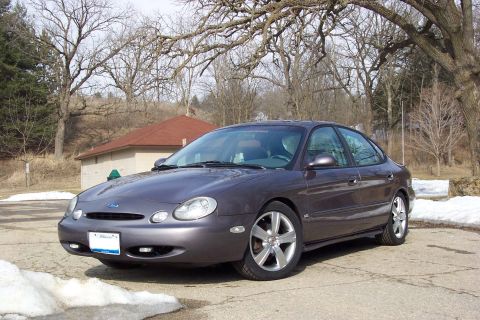 1996 Ford Taurus - A gray 1996 Ford Taurus sedan is parked in an outdoor lot during winter.