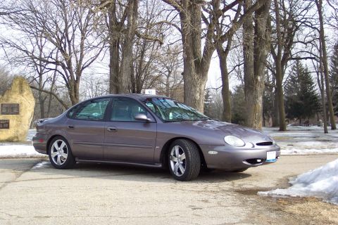 1996 Ford Taurus - A gray Ford Taurus is parked outside in a winter setting with snow on the ground and bare trees.
