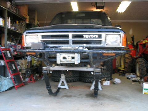 1986 Ford F-150 - A Toyota truck is shown in a garage, lifted on jack stands with a winch attached to its front bumper.