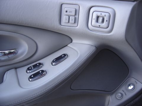 1997 Lincoln Mark VIII - Close-up of a car's interior door panel, showing window controls and mirror adjustment buttons.