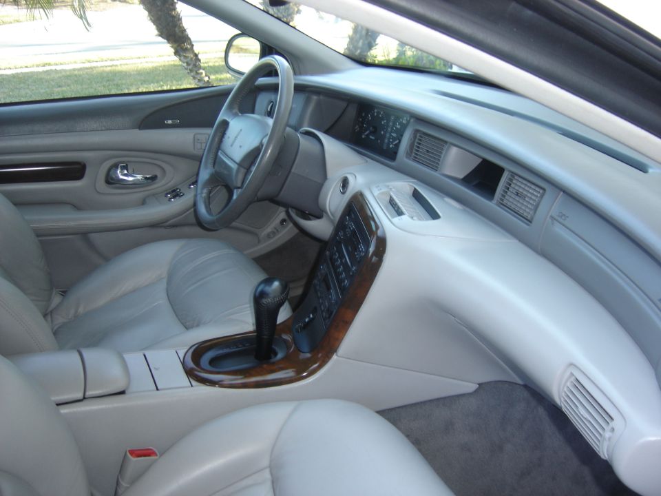 Gray leather car interior with wood-trim console, shifter, steering wheel and dashboard
