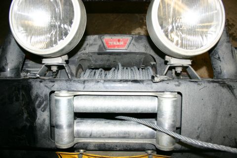 2003 Jeep TJ - The front of a vehicle is equipped with a WARN winch and two large spotlights.