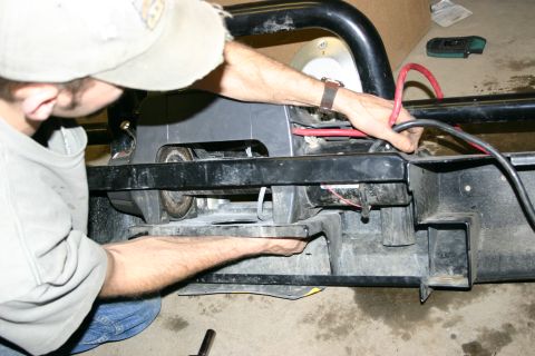 2003 Jeep TJ - A person works on installing a winch onto the front bumper of a 2003 Jeep TJ.