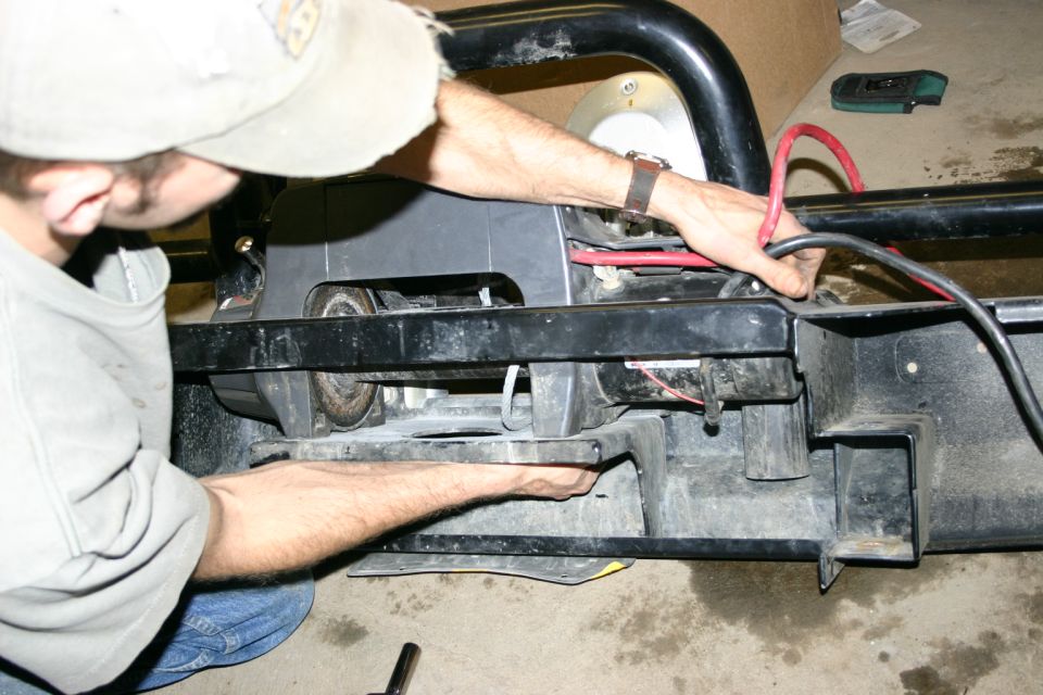 Black winch mounted on a 2003 Jeep TJ bumper, with red and black cables connected