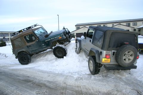 2003 Jeep TJ - Two Jeeps navigate a snowy incline, one with a roof rack and the other viewed from the rear.