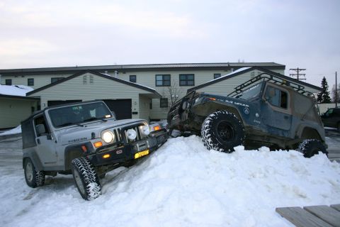 2003 Jeep TJ - Two Jeep Wranglers navigate a snowdrift, their off-road capabilities in winter conditions.