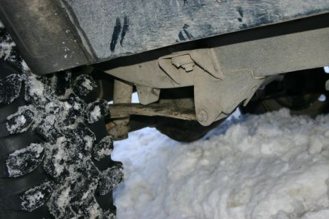 2003 Jeep TJ - The undercarriage of a vehicle is visible, covered in snow, with a large tire in the foreground.