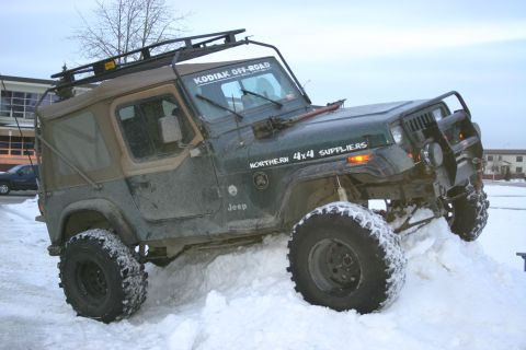 2003 Jeep TJ - A green Jeep Wrangler navigates through a snowdrift, displaying "KODIAK OFF-ROAD" and "NORTHERN 4X4 SUPPLIERS" decals.