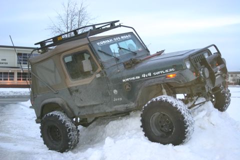 2003 Jeep TJ - This modified Jeep Wrangler navigates a snowy terrain, its off-road capabilities with large tires and a roof rack.