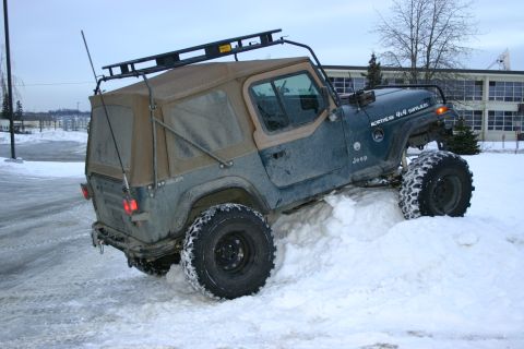 2003 Jeep TJ - 2003 Jeep TJ navigating a snowy terrain with its off-road tires.