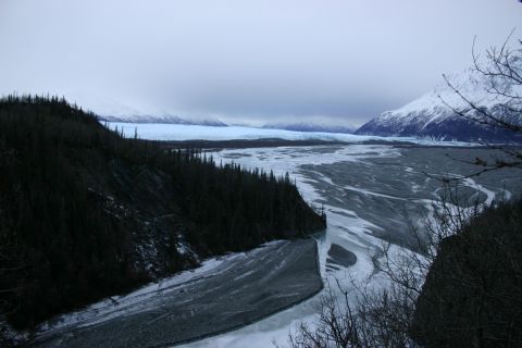 2003 Jeep TJ - A vast, frozen river winds through a valley under a cloudy sky, with a glacier visible in the background.