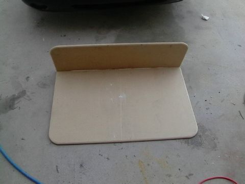 1999 Ford Taurus - A cardboard template rests on a concrete floor, with a portion of a black car bumper overhead.