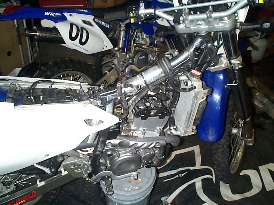 Yamaha dirt bike mid-service with engine top end exposed in a garage
