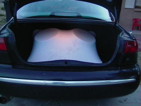 1999 Ford Taurus - Rear view of a black sedan with its trunk open, containing a large white object.