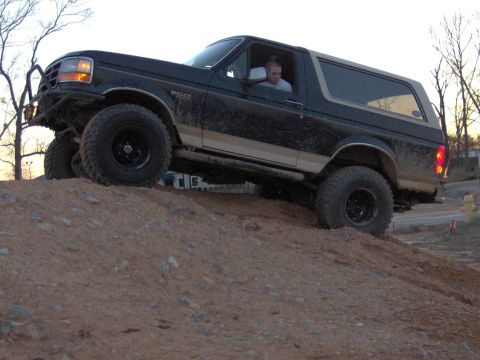 1993 Ford Bronco - Black 1992 Ford Bronco with tan trim is shown driving up a dirt hill.