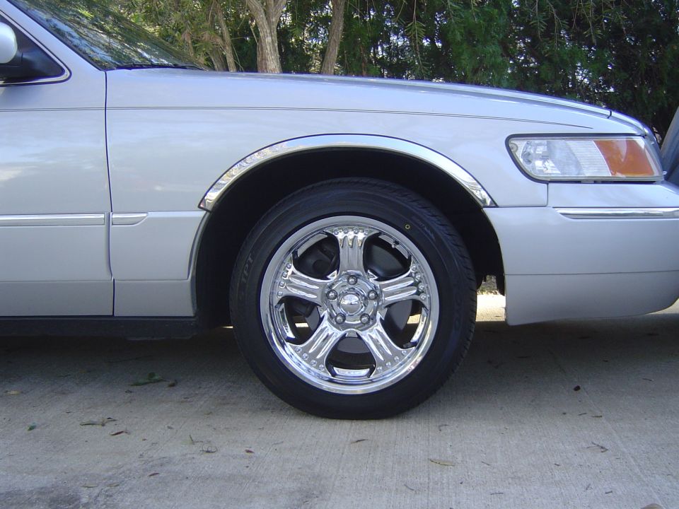Chrome five-spoke aftermarket wheel on the front corner of a silver sedan