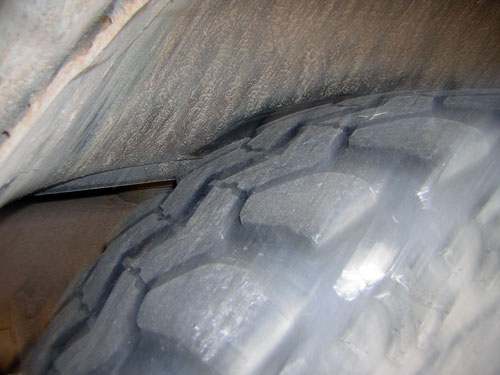 Inside wheel well showing oversized tire tread close to inner fender, tight clearance