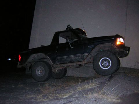 1995 Ford Bronco - A dark green 1995 Ford Bronco is seen from a 3/4 front angle, parked on an incline at night.