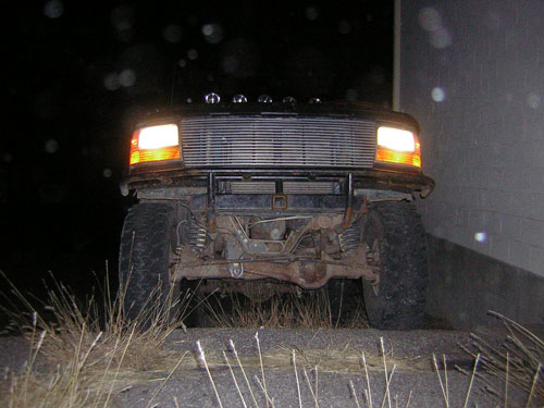 1995 Ford Bronco front view at night, headlights on, showing grille and suspension