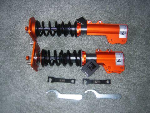 1994 Ford Probe - Two K-Sport coilover suspension assemblies, orange bodies and black springs, are laid out with their adjustment wrenches.