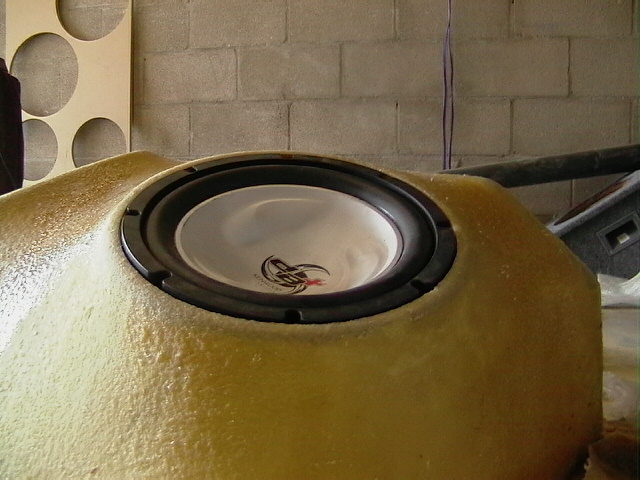 Custom fiberglass subwoofer enclosure with a speaker mounted in it. Text on the bottom right reads SUPERMOTORS