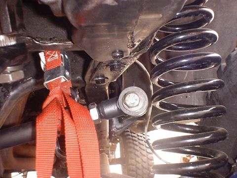 1988 Ford Bronco - This image shows the undercarriage of a vehicle, focusing on the suspension system and a red strap.
