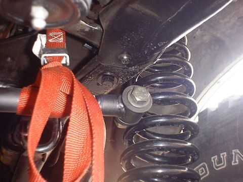 1988 Ford Bronco - Close-up view of a vehicle's suspension system, showing a coil spring and a red strap.