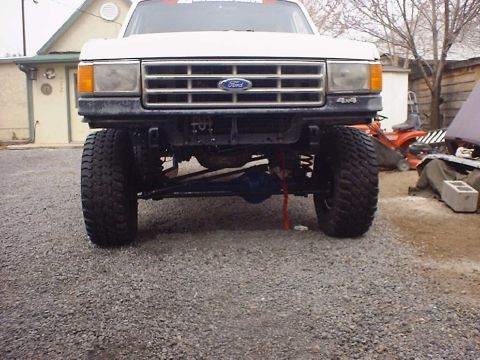 1988 Ford Bronco - Front view of a white 1988 Ford Bronco, a lifted suspension and visible 4x4 badging.