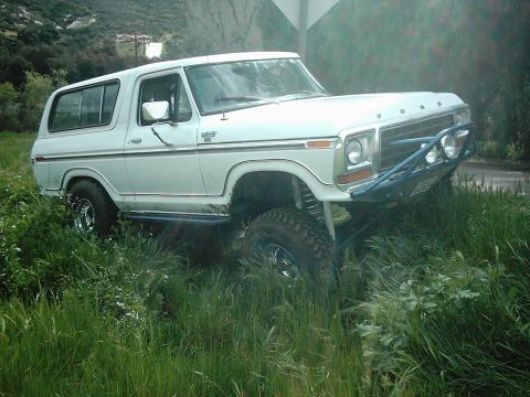 1978 Ford Bronco - This white 1978 Ford Bronco is equipped with a blue off-road bumper and large tires, suggesting it is ready for challenging terrain.