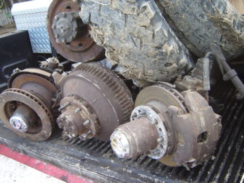 1992 Ford Bronco - Collection of used truck brake components and a large tire in a pickup truck bed.