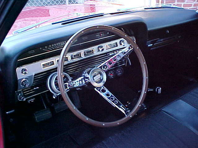 1967 Ford Galaxie interior with wood-rim steering wheel, chrome dash trim, and black bench seat