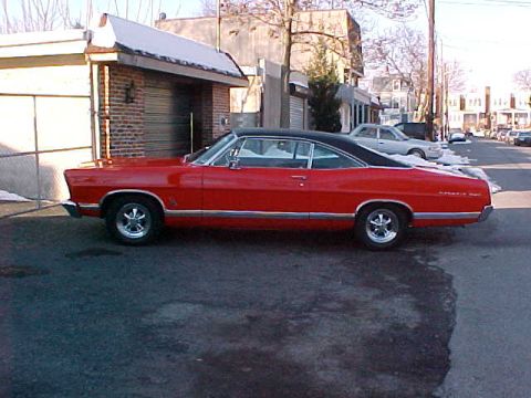 1967 Ford Galaxie - A red 1967 Ford Galaxie coupe with a black vinyl top is parked on a street.