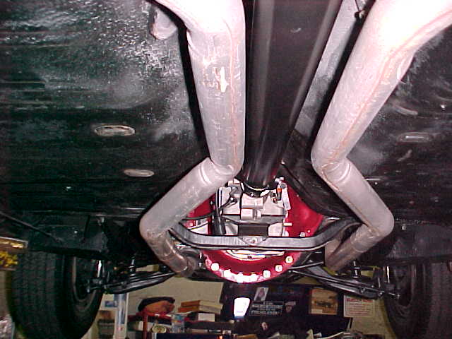 Underside of car showing red differential, dual gray exhaust pipes and rear suspension