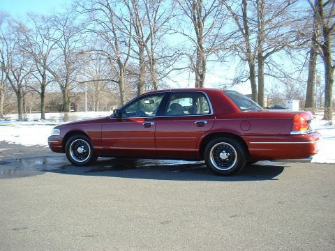 1999 Ford Crown Victoria - Side view of a red sedan with black steel wheels parked outdoors in winter.