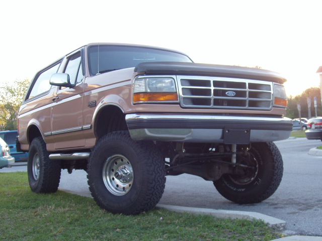 Two-tone brown lifted Ford Bronco SUV, front three-quarter view on grass