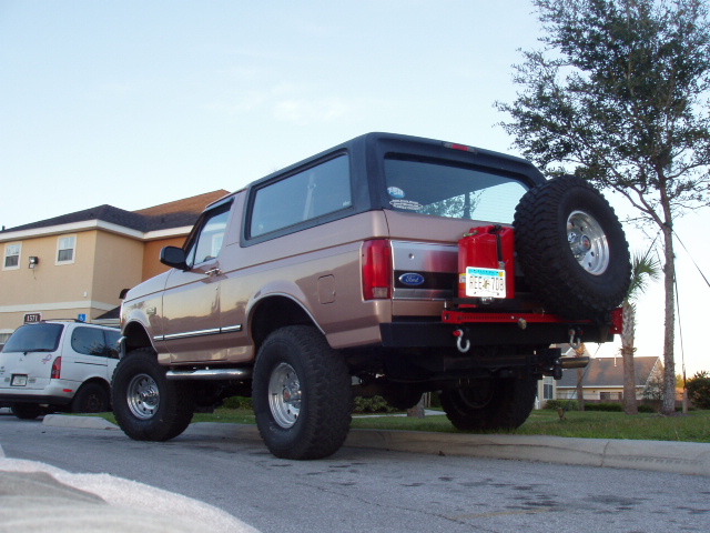 Lifted two-tone tan Ford Bronco SUV rear view with spare tire and big off-road tires