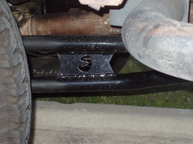 Welded S-stamped traction bar bracket under a lifted truck near exhaust